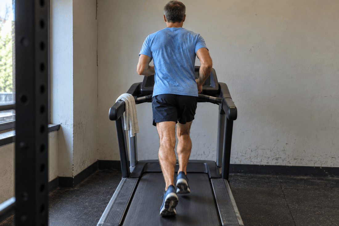 AI-generated illustration of a male runner from behind on a single treadmill in a worn gym corner.